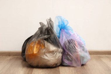 Beyaz duvarın yanında çöp torbaları var.