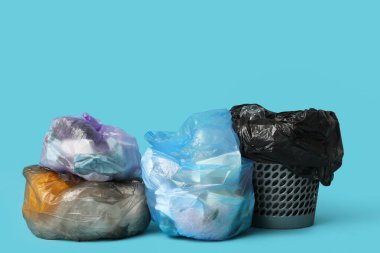 Mavi arka planda çöp kutusu ve çöp torbaları