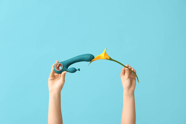 Женские руки с вибратором и калла лилия на цветном фоне