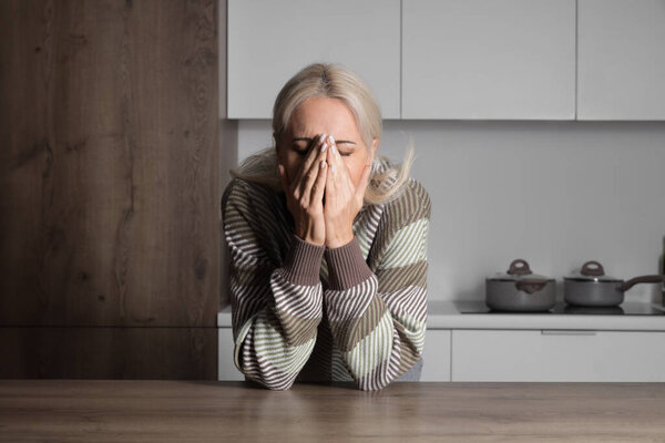 Mature woman having panic attack in kitchen