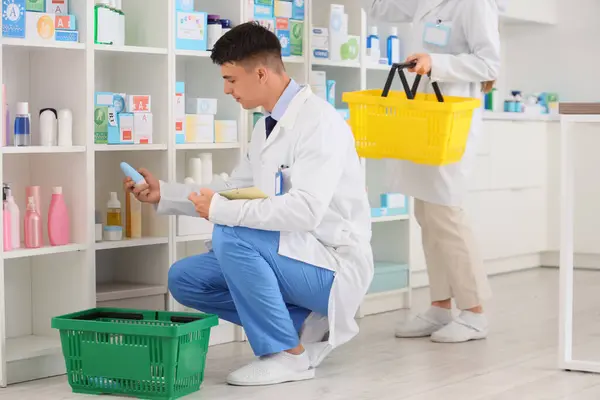 stock image Young pharmacists packing orders into baskets at pharmacy