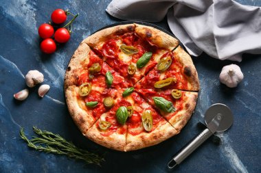 Lezzetli pizzalı kompozisyon, malzemeler ve mavi arka planda kesici.