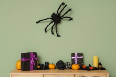 Cadılar Bayramı için hediye kutuları, kafatası, balkabağı, mumlar ve yeşil duvardaki örümcek