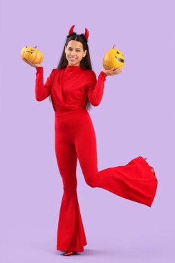 Leylak arka planında Cadılar Bayramı balkabakları olan genç bir kadın.