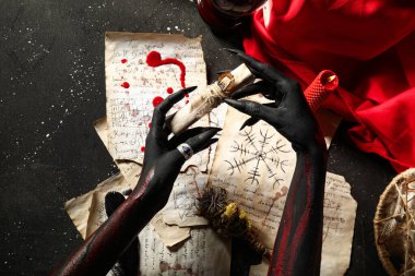 Sihirli özellikleri olan kanlı cadı elleri ve grunge siyah arka planda büyü kağıtları, üst görünüm. Cadılar Bayramı
