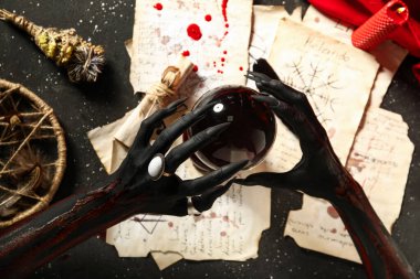 Sihirli özellikleri olan kanlı cadı elleri ve grunge siyah arka planda kristal küre, üst görünüm. Cadılar Bayramı