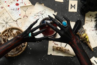 Sihirli özellikleri olan kanlı cadı elleri ve grunge siyah arka planda kristal küre, üst görünüm. Cadılar Bayramı