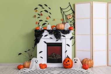 Yeşil duvarın yanındaki şöminede birçok farklı Cadılar Bayramı süslemeleri var.