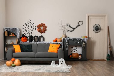 Kanepesi, şöminesi ve farklı Cadılar Bayramı süslemeleri olan festival salonu.