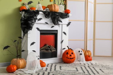 Yeşil duvara karşı şöminenin yanında farklı Cadılar Bayramı dekorasyonları.