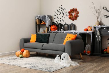 Kanepesi, şöminesi ve farklı Cadılar Bayramı süslemeleri olan festival salonu.