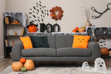 Kanepesi, şöminesi ve farklı Cadılar Bayramı süslemeleri olan festival salonu.