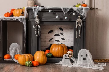 Beyaz duvarın yanında farklı Cadılar Bayramı süslemeleri olan modern şömine.