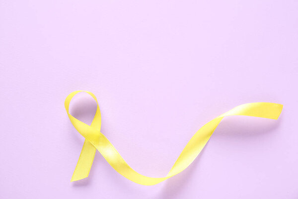 Yellow ribbon on lilac background. World Cancer Day