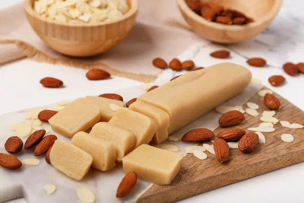 stock image Cutting board with tasty marzipan, almond nuts and flakes on light table