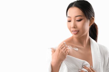 Güzel Asyalı kadın beyaz arka plana vücut kremi sürüyor.