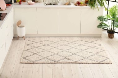 Modern mutfağın içinde şık halı, çöp kutusu ve beyaz tezgahlar var.