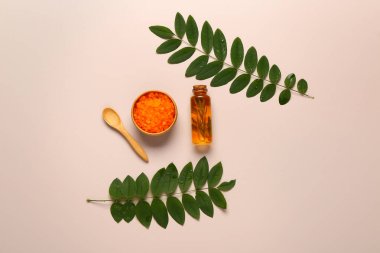 Gri arka planda yapraklı ve deniz tuzlu bir şişe kozmetik yağı.