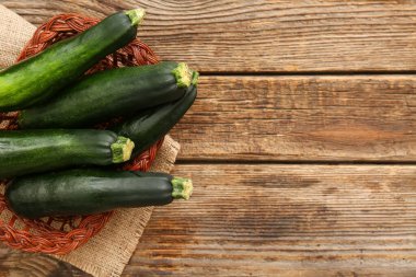 Tahta arka planda yeşil kabaklı sepet.