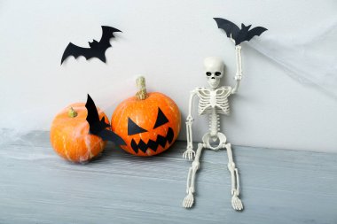 Cadılar Bayramı kutlaması için balkabakları, İskelet ve kağıt yarasalar gri ahşap masada