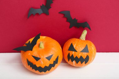 Cadılar Bayramı kutlaması için balkabakları ve masa üzerinde kağıt yarasalar, yakın plan.