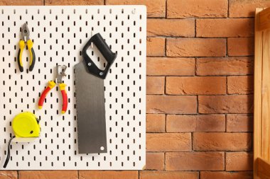 Atölyedeki tuğla duvarda inşaat aletleri olan tahta.