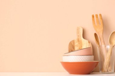 Mutfak gereçleri ve kaseler bej duvarın yanındaki ahşap masada.