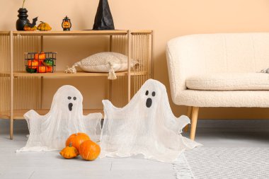 Cadılar Bayramı için dekore edilmiş oturma odasının içinde kanepe ve raf ünitesi var.