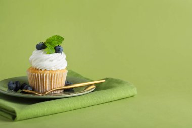 Yeşil arka planda yaban mersinli bir tabak lezzetli kek.