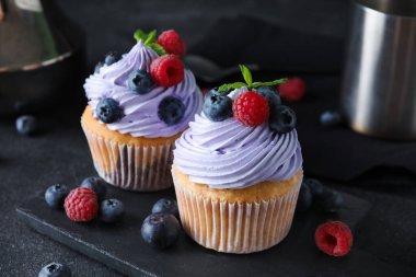 Böğürtlenli, ahududulu ve siyah arkaplanlı lezzetli kekler.