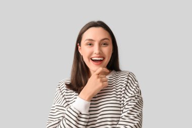 Gri arka planda gülümseyen genç kadın