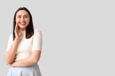 Gri arka planda gülümseyen genç kadın