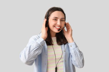 Gri arka planda kulaklık takan mutlu bayan teknik destek ajanı