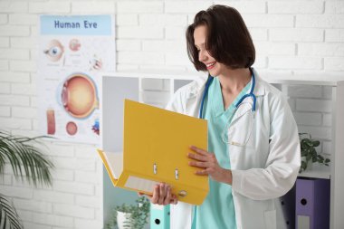 Klinikte dosyası olan güzel bir kadın doktor.