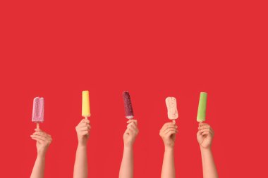 Kırmızı arka planda farklı tatlı dondurmalı kadın elleri.