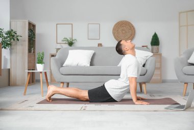 Evdeki paspasın üzerinde spor yapan genç adam.