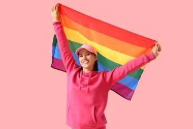 Pembe arka planda LGBT bayrağı olan güzel genç bir kadın.