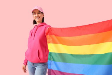 Pembe arka planda LGBT bayrağı olan güzel genç bir kadın.