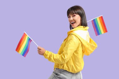 Leylak arka planında LGBT bayrakları olan güzel genç bir kadın.