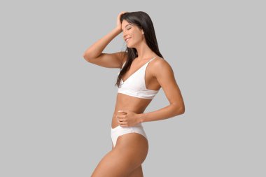 Güzel, genç, mutlu, gri arka planda iç çamaşırlı, pozitif kadın.