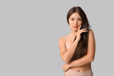 Gri arka planda iç çamaşırlı güzel, genç Asyalı kadın.