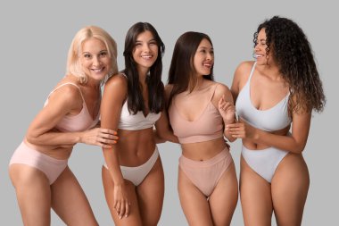 Güzel, farklı, mutlu, pozitif kadınlar gri arka planda gülüyorlar.