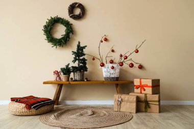 Odanın içinde ahşap banklar, Noel ağaçları ve çelenkler var.