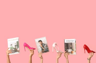 Farklı dergilere sahip kadın elleri ve pembe arka planda şık topuklu ayakkabılar.