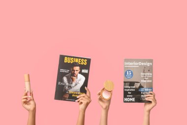 Farklı dergilere sahip kadın elleri ve pembe arka planda dekoratif kozmetik ürünler.