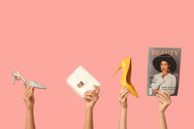 Dergisi olan kadın elleri, şık çantalar ve pembe arka planda topuklu ayakkabılar.