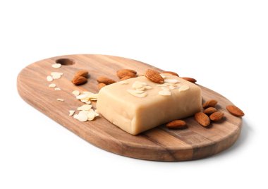 Lezzetli badem ezmeli ahşap tahta, badem fıstığı ve beyaz arka planda pullar.