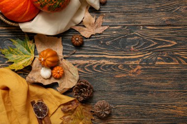 Mumlar, düşmüş yapraklar ve ahşap arka planda çam kozalakları olan kompozisyon