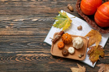 Ahşap arka planda farklı mumlar, kitap ve sonbahar dekoru olan kompozisyon