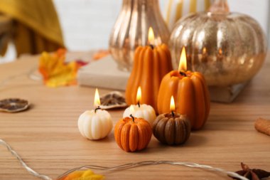 Balkabağı şeklinde mumlar yakmak, sonbahar yaprakları ve evdeki sehpanın üzerinde kuru turkuazlar, yakın çekim.